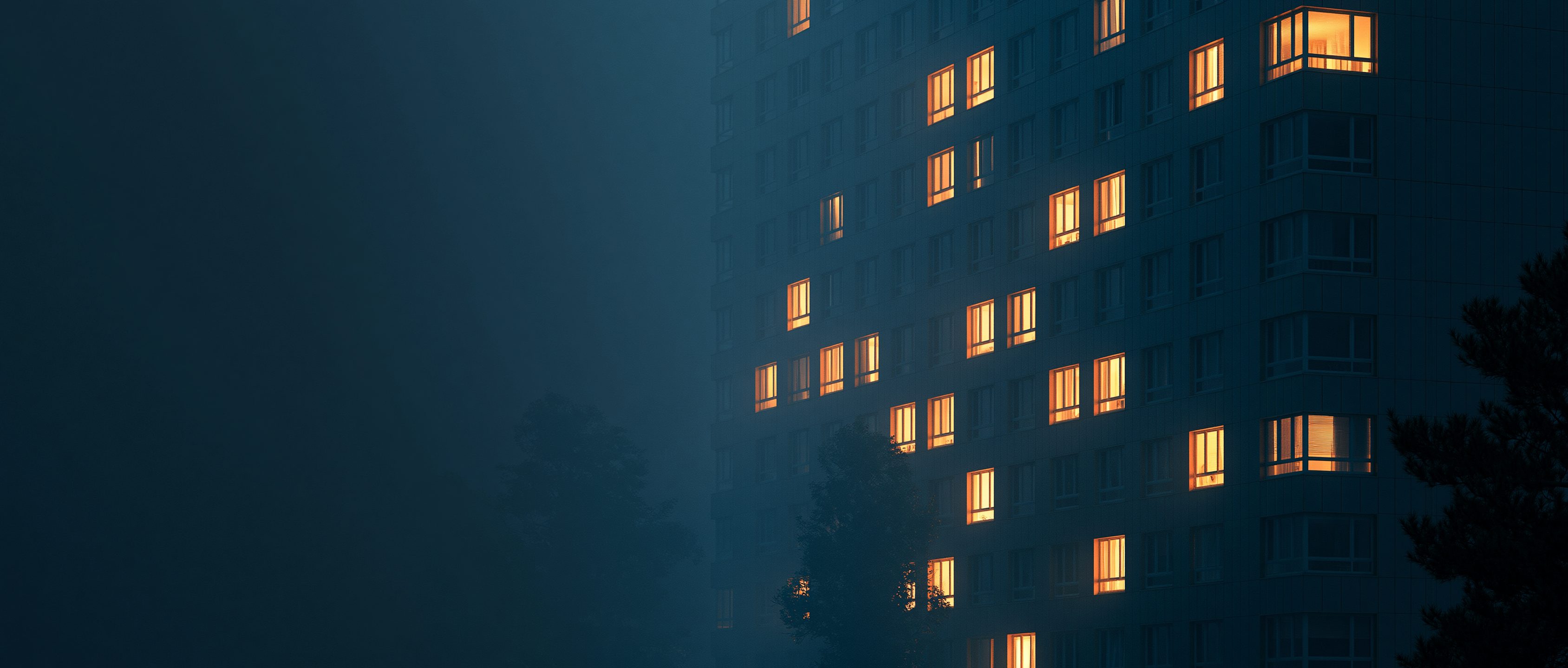 An apartment building at dusk, windows warmly lit